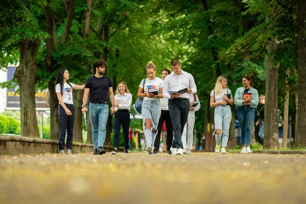 一群年轻的大学生一起走在外面 带着书本和背包 彼此交谈着回到学校 — 图库照片
