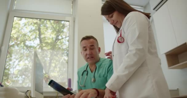 シニアドクター 近代的なオフィスルームで一緒に働いている間 高齢者のX線画像と医療成果について話し合う — ストック動画