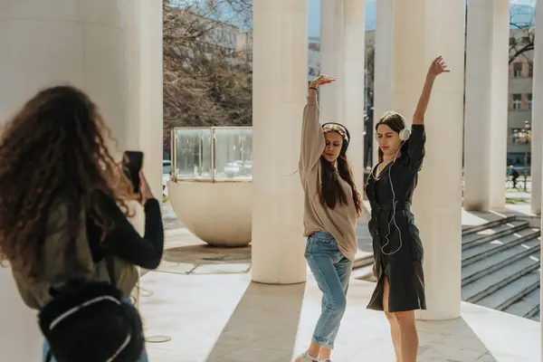 Kıvırcık Saçlı Kız Iki Esmer Arkadaşının Kulaklıklarıyla Müzik Dinlerken Dans — Stok fotoğraf