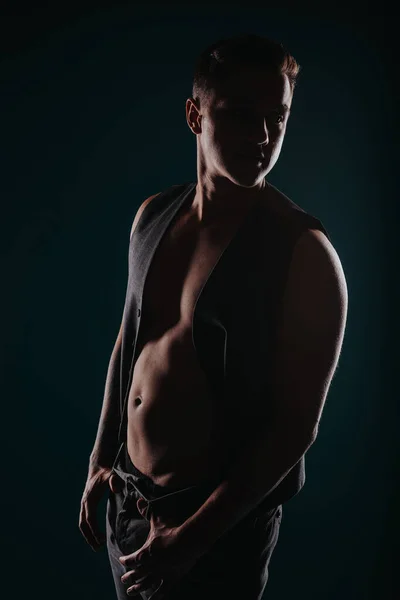 フィットマンは 黒い背景に対するスタジオシルエットでの体の変換の結果を示す筋肉を柔軟にします — ストック写真