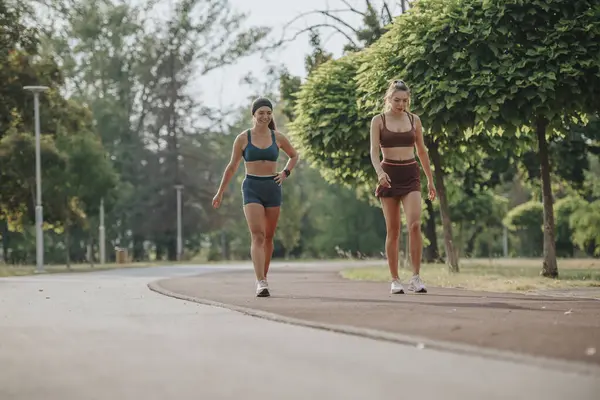 緑の公園で屋外でジョギングする2人のフィットガールは 健康的なライフスタイルとアウトドアのフィットネスを刺激します — ストック写真