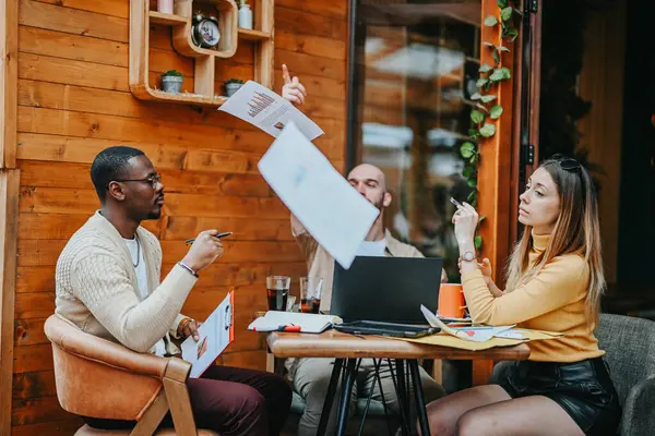 A group of business executives discuss market analysis, financial planning, and growth hacking at an outdoor coffee bar. They collaborate on strategies for their start-up, targeting the urban market.