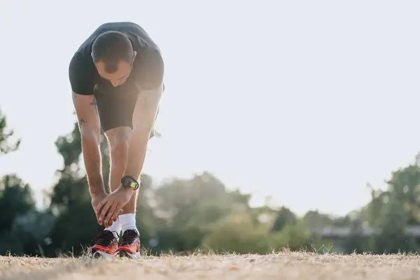 体を伸ばし 暖める公園で屋外スポーツを実践するフィットマン — ストック写真