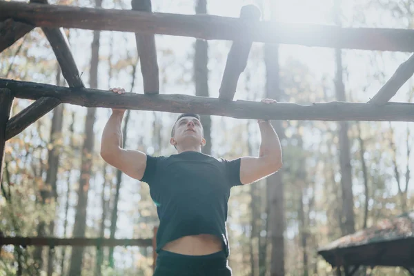 Active sportsperson enjoying outdoor adventure in a green forest landscape. Hiking, doing pull ups on a sunny day surrounded by trees. Embracing nature for a healthy, adventurous weekend.