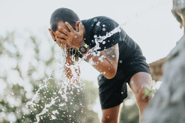 公園のアクティブな男はさわやかになり トレーニングから休憩を取ります 噴水から水で顔を洗う — ストック写真