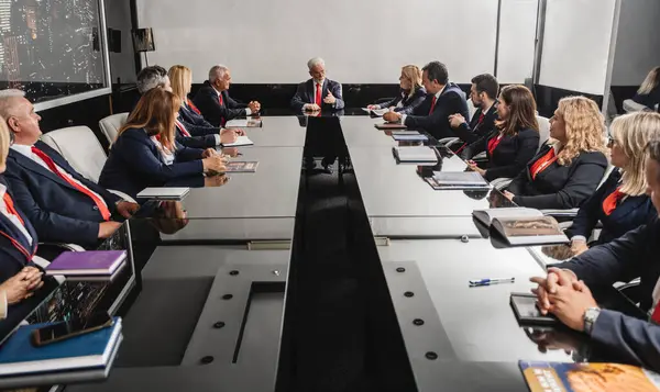 Business, executives and partners gather in a modern office conference room for a board meeting. They discuss market analysis, profit growth and making suggestions for better efficiency and results.