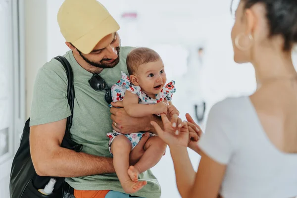 赤ん坊の女の子を抱えている父 医者を待っている間に赤ちゃんの娘と遊ぶ母親は 医療チェックアップを呼び出します — ストック写真