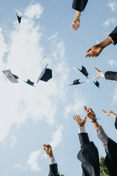 stock image Young graduates celebrate graduation in a park, throwing their caps in the air. They cherish achieved goals, teamwork, and create beautiful memories with friends and faculty.