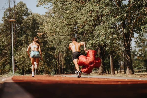 コーカサスランナーは公園でスプリントし パラシュートでトレーニングを行います 彼らは より良いボディ形状と強い筋肉のために努力し 屋外の運動や競争を楽しんでいます — ストック写真