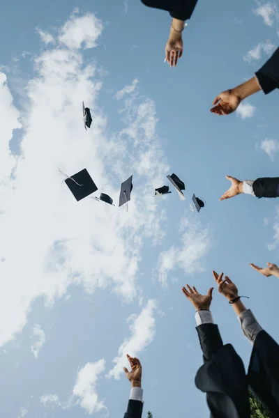 stock image Graduating students in a park, celebrating their achievements with uniform, gown, and cap. They throw their caps, creating beautiful memories with friends and faculty colleagues.