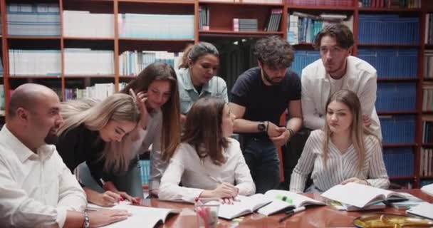 Ett Livligt Universitetsbibliotek Samlas Grupp Olika Högskolestudenter Runt Ett Bord — Stockvideo