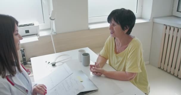 一位年轻而有经验的女医生讨论她的老年女病人的健康问题 为克服疾病提供建议和适当的治疗 — 图库视频影像
