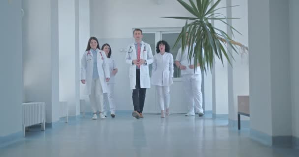 Grupo Médicos Caminando Discutiendo Moderno Pasillo Del Hospital — Vídeo de stock