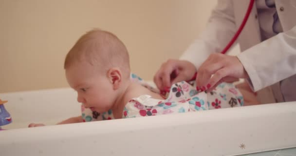 아기를 검사하는 소아과 청진기를 사용하여 그녀는 어머니가 그것으로 놀고있는 아기를 — 비디오