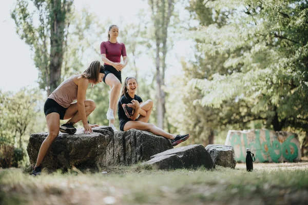 stock image Fit girls stretch and train outdoors in a city park, enjoying the sunny day. They maintain a positive atmosphere while engaging in sports activities and staying fit.