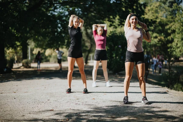 都市公園の陽気な女性は トレーニングのために一緒に伸びて温めます ポジティブな雰囲気の中で屋外スポーツを楽しむフィットガールズ — ストック写真