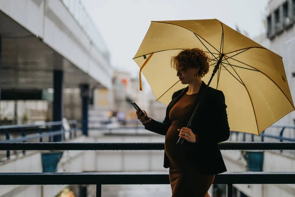 雨の日に傘を持っている間 大きなビジネスセンターに立っている妊娠中のビジネスマン — ストック写真