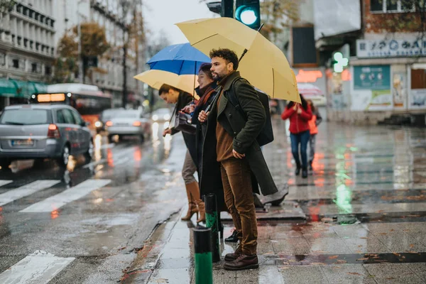 傘を持っているビジネスの人々は 大通りに通る緑色の交通灯を待っています 彼らは雨の日に取り組んでいる — ストック写真