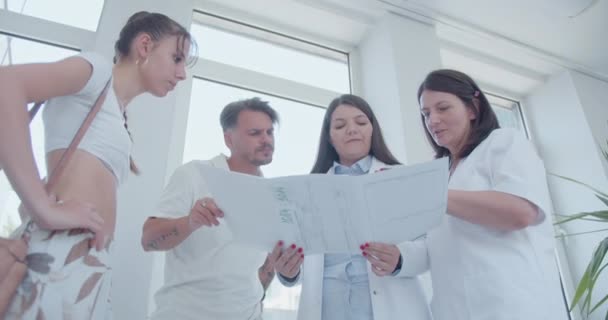 Zkušené Ženské Specialistky Čtou Vysvětlují Svým Mladým Pacientům Lékařské Výsledky — Stock video