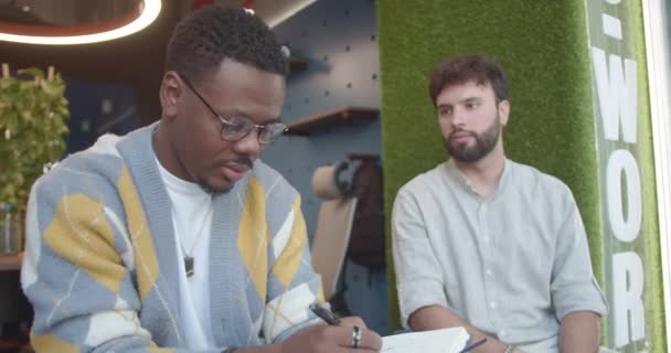 Ein Schwarzer Mann Zeichnet Seinen Weißen Kollegen Während Einer Arbeitspause — Stockvideo