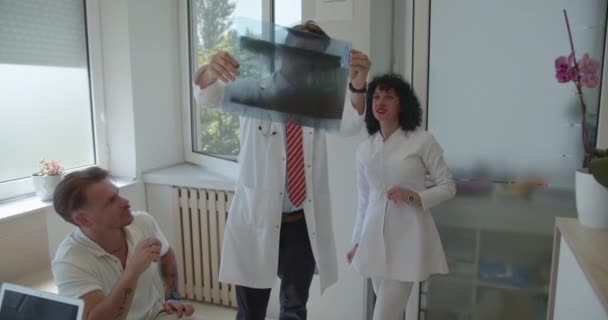 Опытный Медицинский Персонал Анализирует Обсуждает Объясняет Рентгеновские Снимки Своему Молодому — стоковое видео