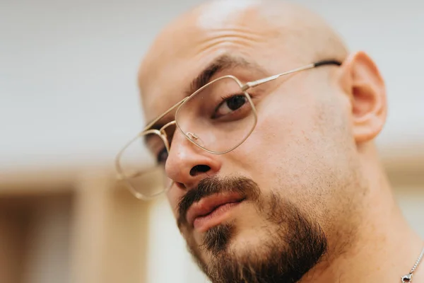 Head shot of young bald man wearing eyeglasses looking at the camera. Portrait photo.