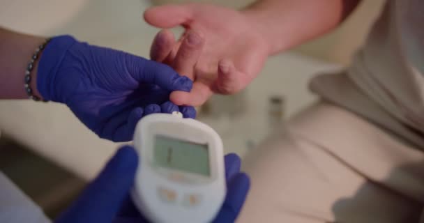 病院の実験室で患者の血糖値をチェックするためにグルコメータを使用して医師のビデオを閉じます — ストック動画