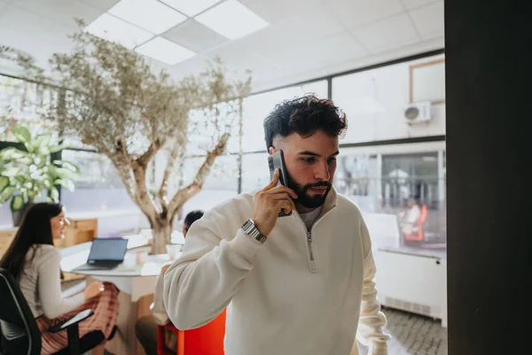 Handsome male person going out of office during phone call.