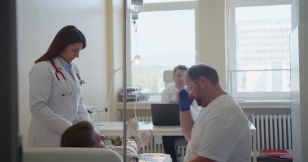 病院で病気の若い患者にIvドリップ注入を与える医師 — ストック動画