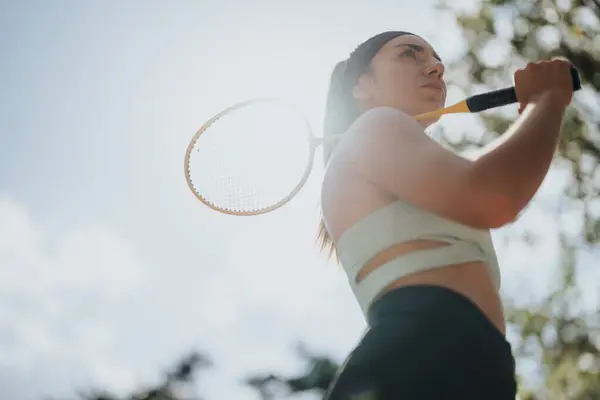 A sports, female person is holding a racket on her shoulder. Low angle view photo. Copy space.