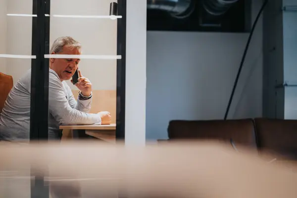 Creative person discussing marketing strategies and business development while having phone call sitting at soundproof phone booth at the office.