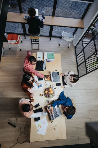 Top view photo of diverse coworkers collaborating on business strategy, working late to meet deadlines and ensure success as a cross-generational team.