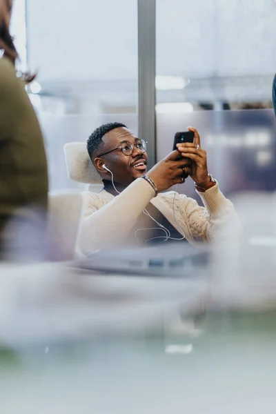 Black male watching videos on his phone and smiling while resting from work.
