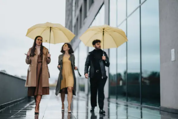 雨の多い都市の設定で黄色い傘で歩いている3人の友人 — ストック写真