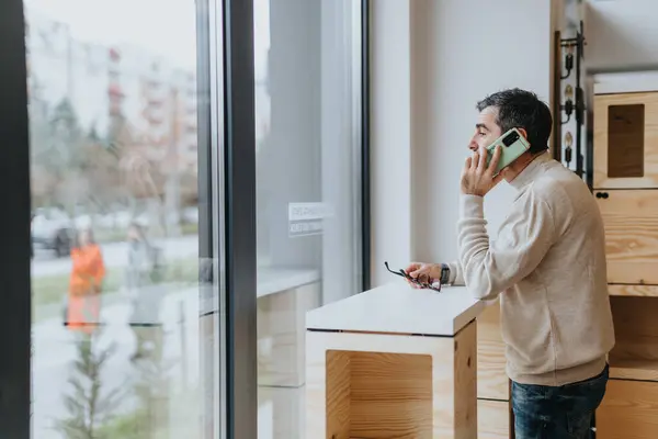 近代的なオフィスに立っているビジネスマンは 自信と戦略的な洗練された電話で重要な取引を交渉します — ストック写真