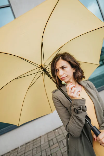 屋外でオーバーキャストされた日に黄色い傘を持っている高価な女性 — ストック写真