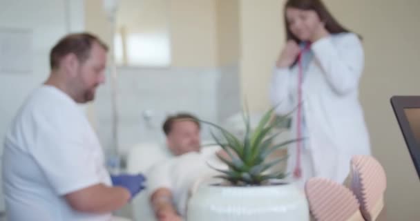 在医院检查年轻病人的中年医生 他们给他静脉滴注或注射维生素 — 图库视频影像