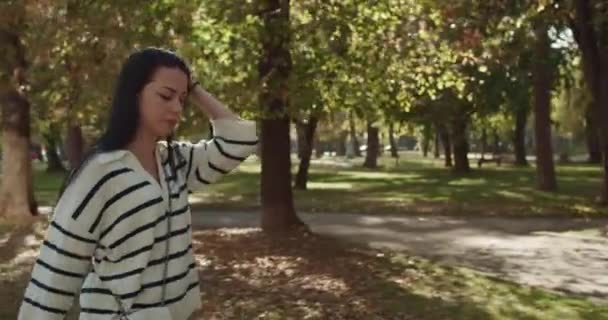 ゴージャスでブルネット 大学生が日当たりの良い クラスの後に市立公園にぶら下がり たくさんの木々とポジティブな雰囲気に囲まれています — ストック動画