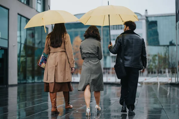 雨の中で一緒に散歩する認識できない個人のバックビュー 反射湿った都会の通りで鮮やかな黄色の傘を保持 — ストック写真