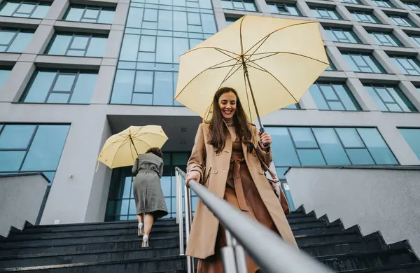 オフィスビルの階段を歩いている黄色い傘を持つスタイリッシュな女性 — ストック写真