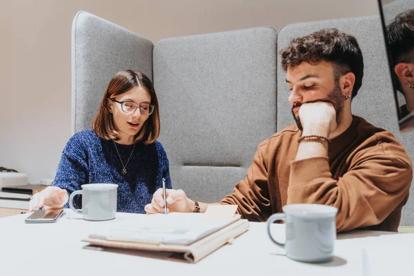 Two young adults engaged in a collaborative work session at a sleek workspace. The image captures the essence of teamwork, creativity, and the professional work environment.