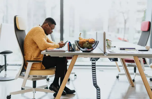 Hombre Negro Sentado Escritorio Trabajo Revisando Teléfono Durante Descanso —  Fotos de Stock