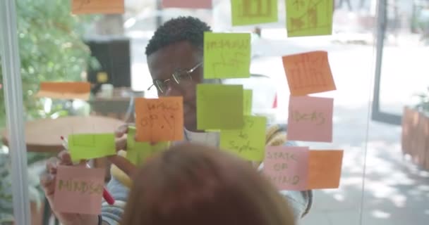 多様な専門家が近代的なオフィスで協力し ガラス板でビジネスアイデアや目標を議論する — ストック動画
