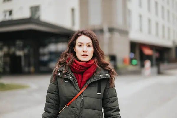 穿着保暖夹克 戴着红围巾的年轻女性 城市生活理念 专注而严肃的表达 — 图库照片