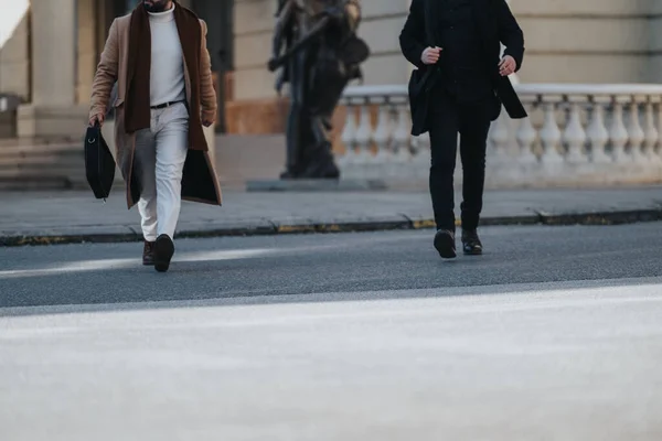 Two professional men walking across the street in stylish outfits.