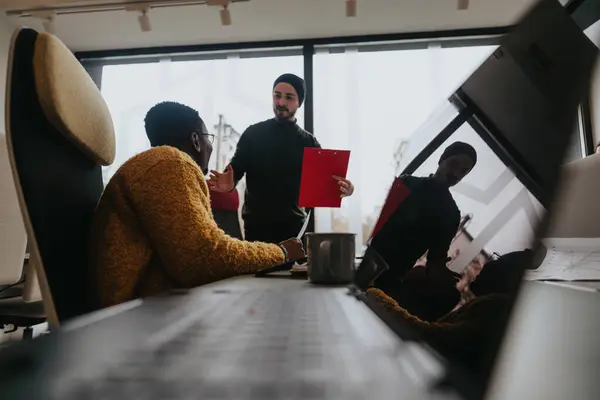 A multicultural team engaged in discussion in a modern office. Colleagues collaborate over documents, embodying teamwork and partnership in a corporate setting.