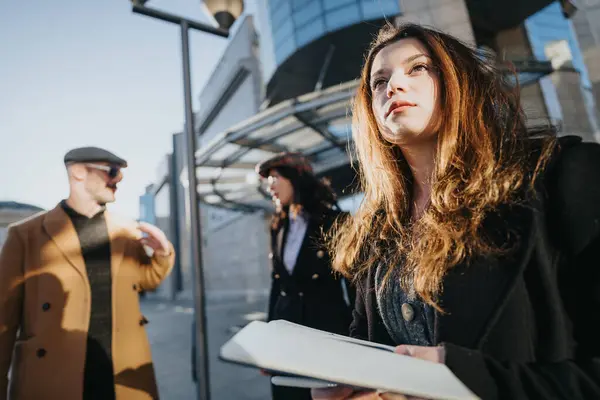 Confident Young Businesswoman Holding Documents Busy Street Colleagues Conversing Soft — Stock Photo, Image