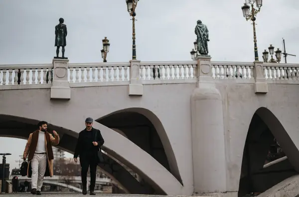 Двое Стильных Мужчин Вступают Беседу Идя Мостом Украшенным Уличными Фонарями — стоковое фото