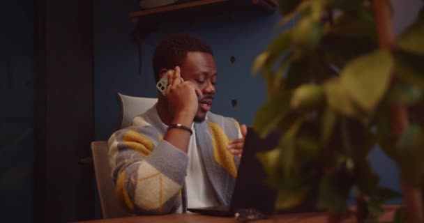 一位年轻 黑人商业领袖坐在市中心一个现代化 漂亮的办公室里 一边打电话 一边与客户或投资者商谈新项目的价格 — 图库视频影像