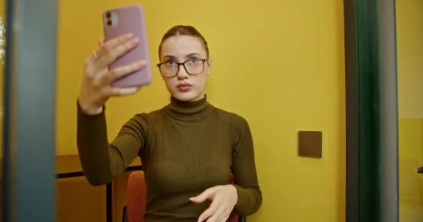 Irodai Nyüzsgés Közepette Egy Női Alkalmazott Játékosan Szelfiket Készít Telefonfülkében — Stock videók